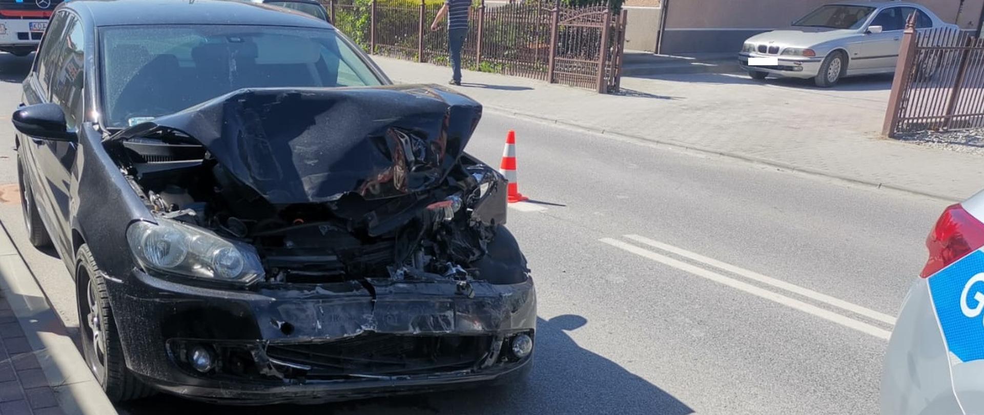 Na zdjęciu widać przód drugiego pojazdu biorącego udział w kolizji, w oddali wóz strażacki OSP Szczucin