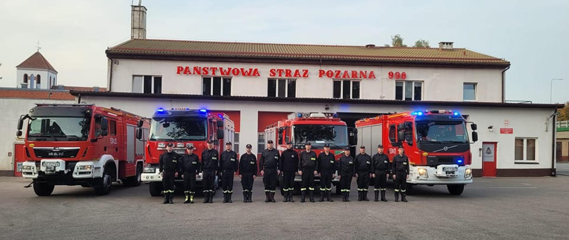 funkcjonariusze JRG Ostróda oraz druhowie OSP Ostróda ustawieni w szeregu przed pojazdami pożarniczymi