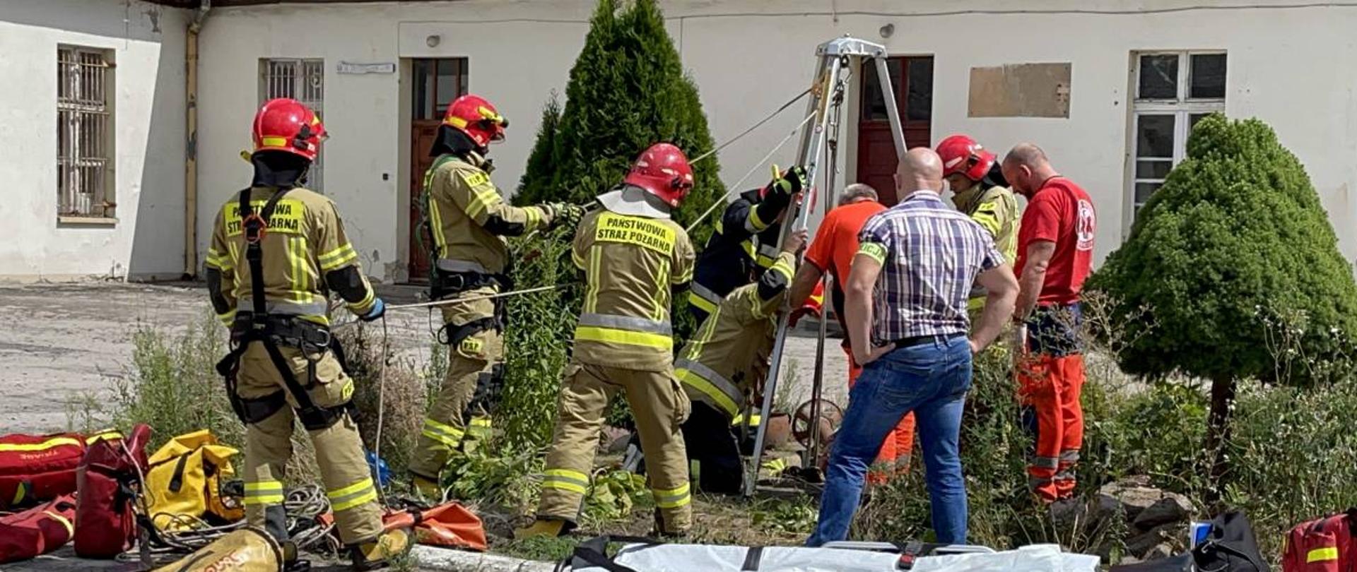 Na zdjęciu widoczni są strażacy, którzy wyciągają dziecko ze studni za pomocą lin.
