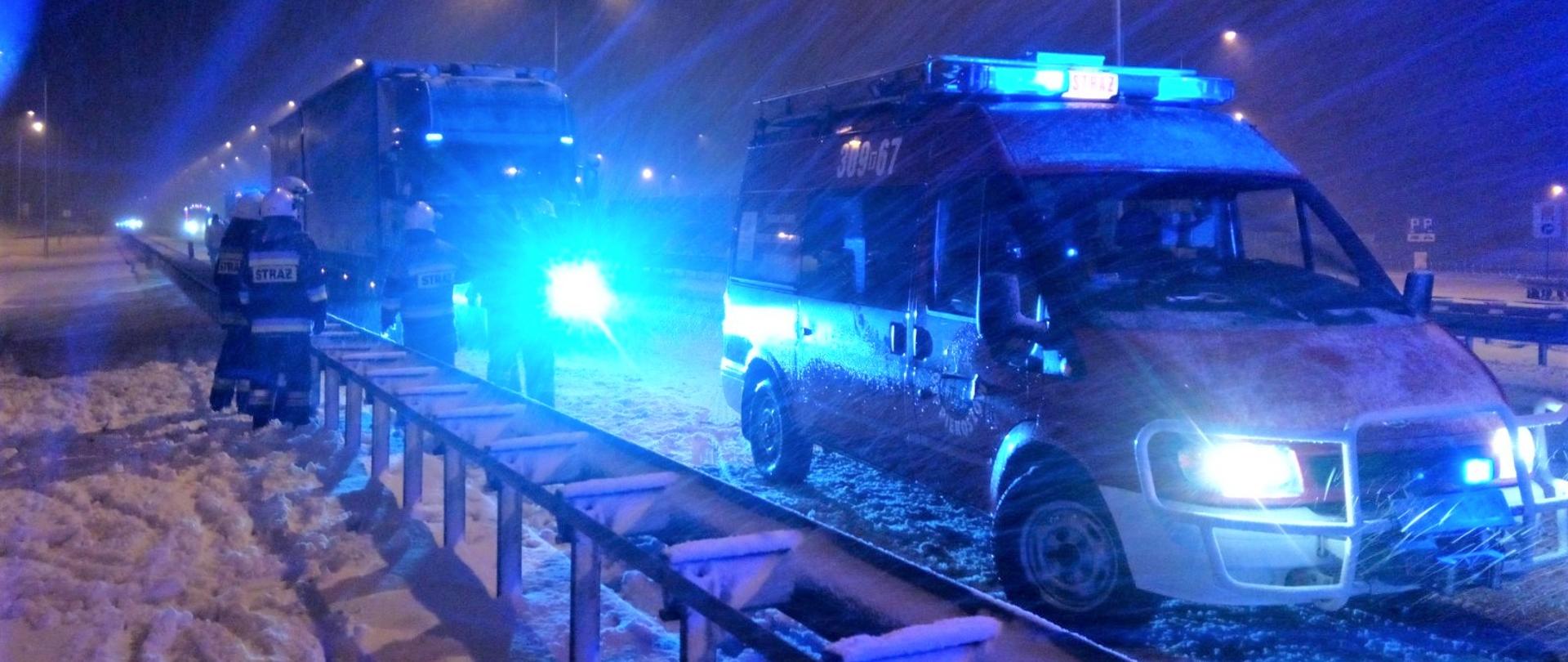 Na zdjęciu widzimy samochód pożarniczy biorący udział w usuwaniu skutków kolizji drogowej. Na pierwszym planie widać bariery energochłonne zaś z tyłu znajduje się samochód ciężarowy, który brał udział w kolizji.