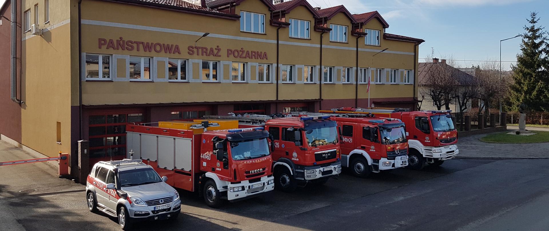 Na zdjęciu plac przed Komendą PSP w Jaśle, na pierwszym planie samochody wyjazdowe. Na drugim planie budynek Komendy.