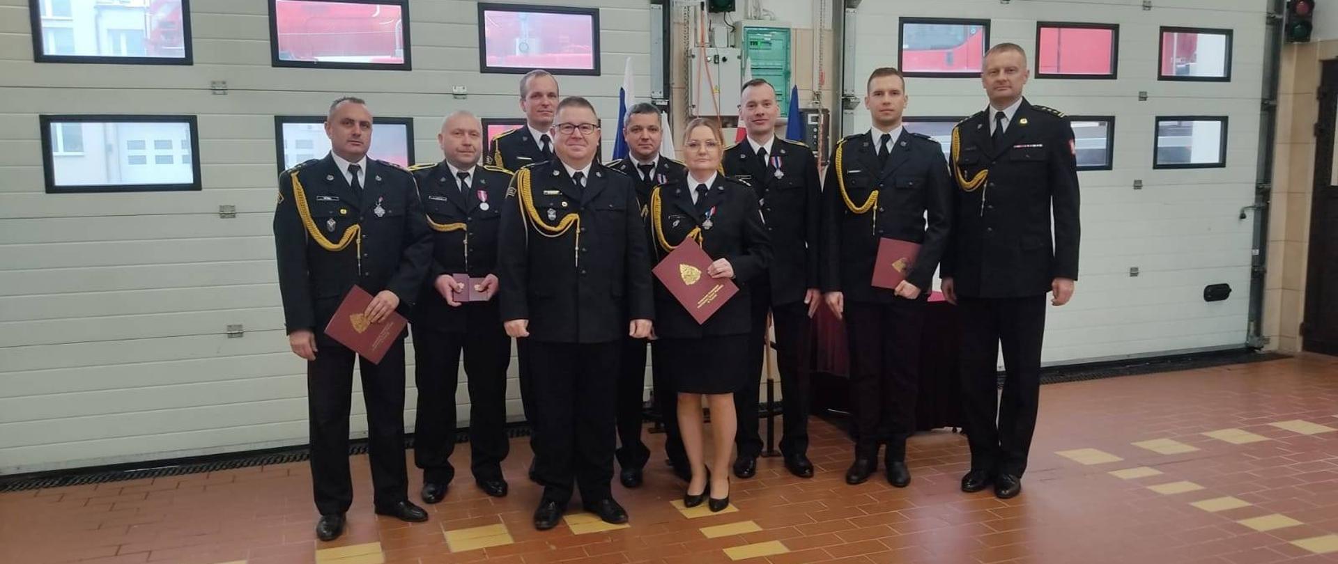 Zdjęcie przedstawia wyróżnionych funkcjonariusz KP PSP Starogard Gdański. W tle bramy garażowe JRG