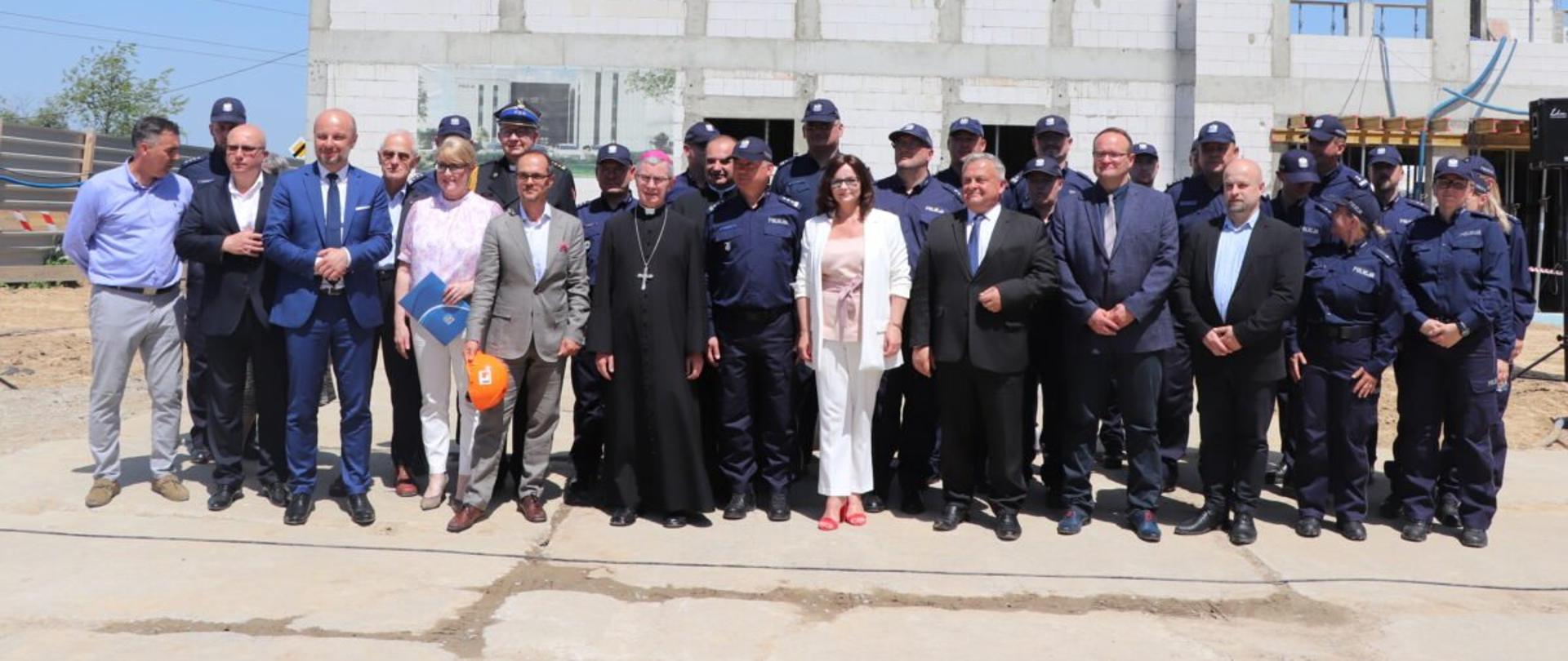Uczestnicy uroczystości podpisania i wmurowania aktu erekcyjnego pod budowę nowej siedziby Komisariatu Policji II na ul. Błogosławionej Karoliny na tle budynku