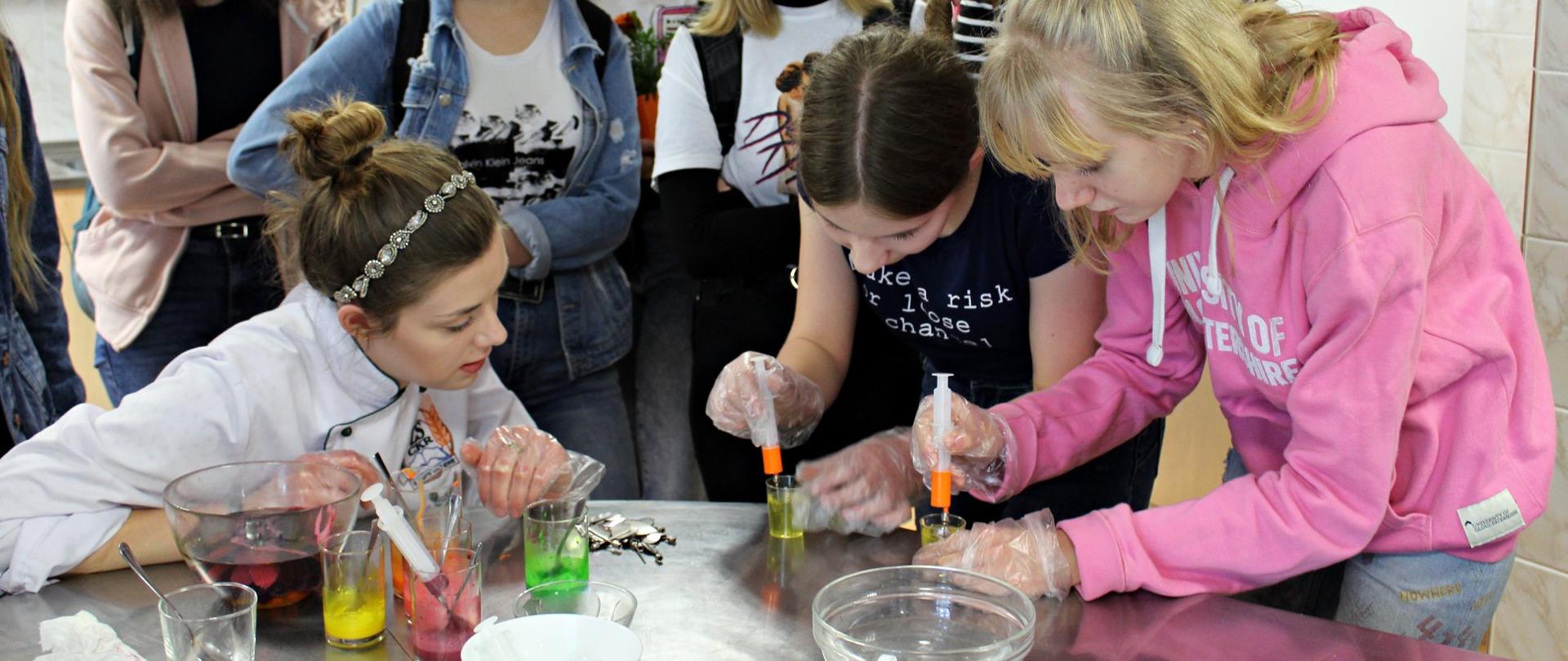 Grupa uczennic wykonuje kolorowe galaretki, kilka innych się przygląda