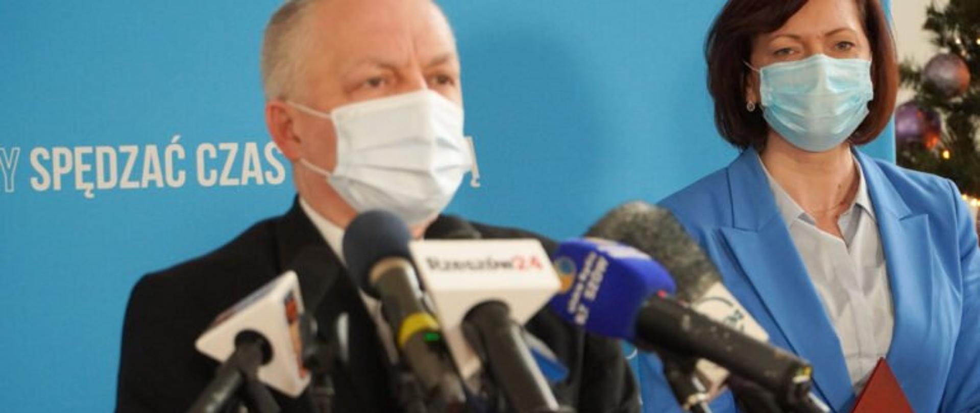 Podkarpacki wojewódzki inspektor sanitarny Adam Sidor zabiera głos podczas konferencji prasowej dotyczącej sytuacji epidemicznej. Obok stoi wojewoda podkarpacki Ewa Leniart. 