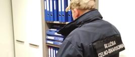 Funkcjonariusz Służby Celno-Skarbowej przy szafie z dokumentacją.