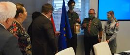 W sali posiedzeń KRRiT, po prawej stronie stoją harcerze z kagankiem Światła. Po lewej stoją Członkowie KRRiT. Pomiędzy nimi flagi Polski i Unii Europejskiej.