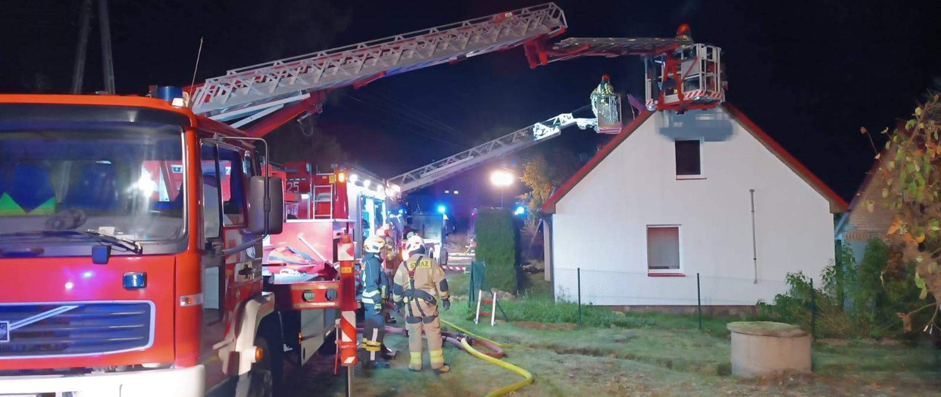 Wóż strażacki i strażacy gaszący pozar domu 