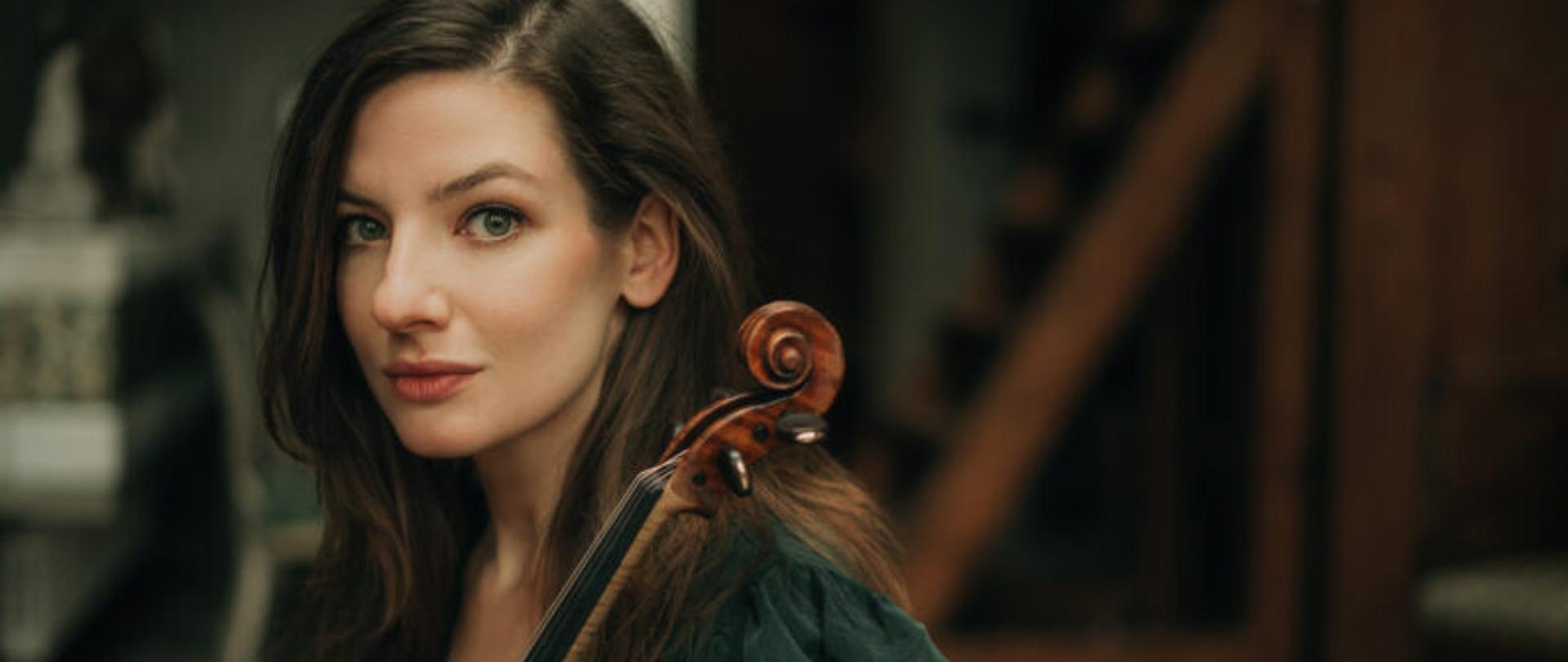 kobieta trzymająca skrzypce na tle rozmytego poddasza