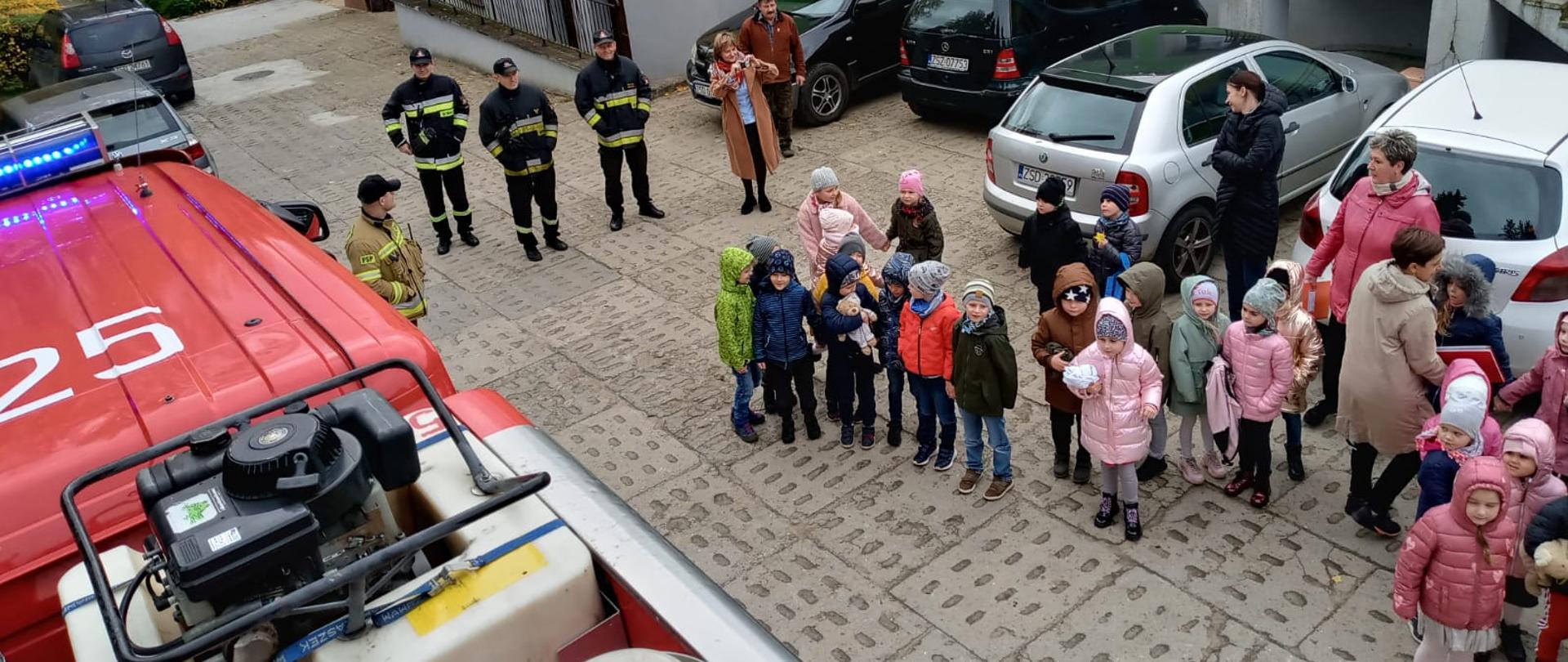 Zdjęcie przedstawia próbną ewakuacją przedszkola w Połczynie-Zdroju. Na pierwszym tle znajduję się dowódca wraz ze strażakami nadzorujący przebieg ewakuacji obok niego znajdują się ewakuowane osoby. Zdjęcie wykonane z dachu wozu strażackiego.