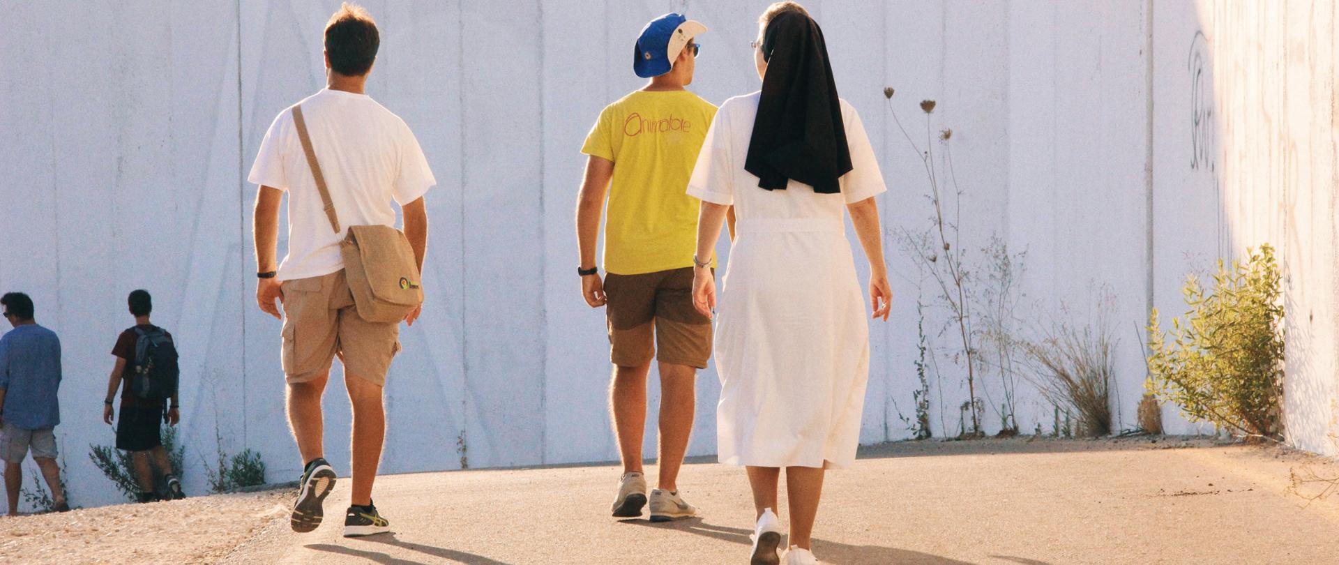 Zdjęcie przedstawia osoby idące w pielgrzymce.