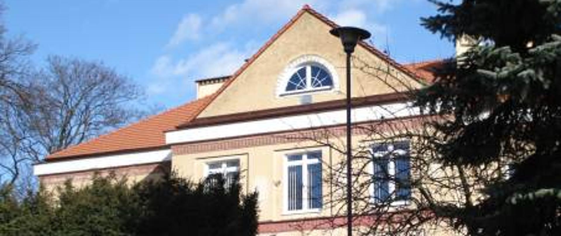 Budynek szkoły zlokalizowany w Kościerzynie przy ul. Dworcowej 12, delikatnie przykryty otaczającą zielenią.