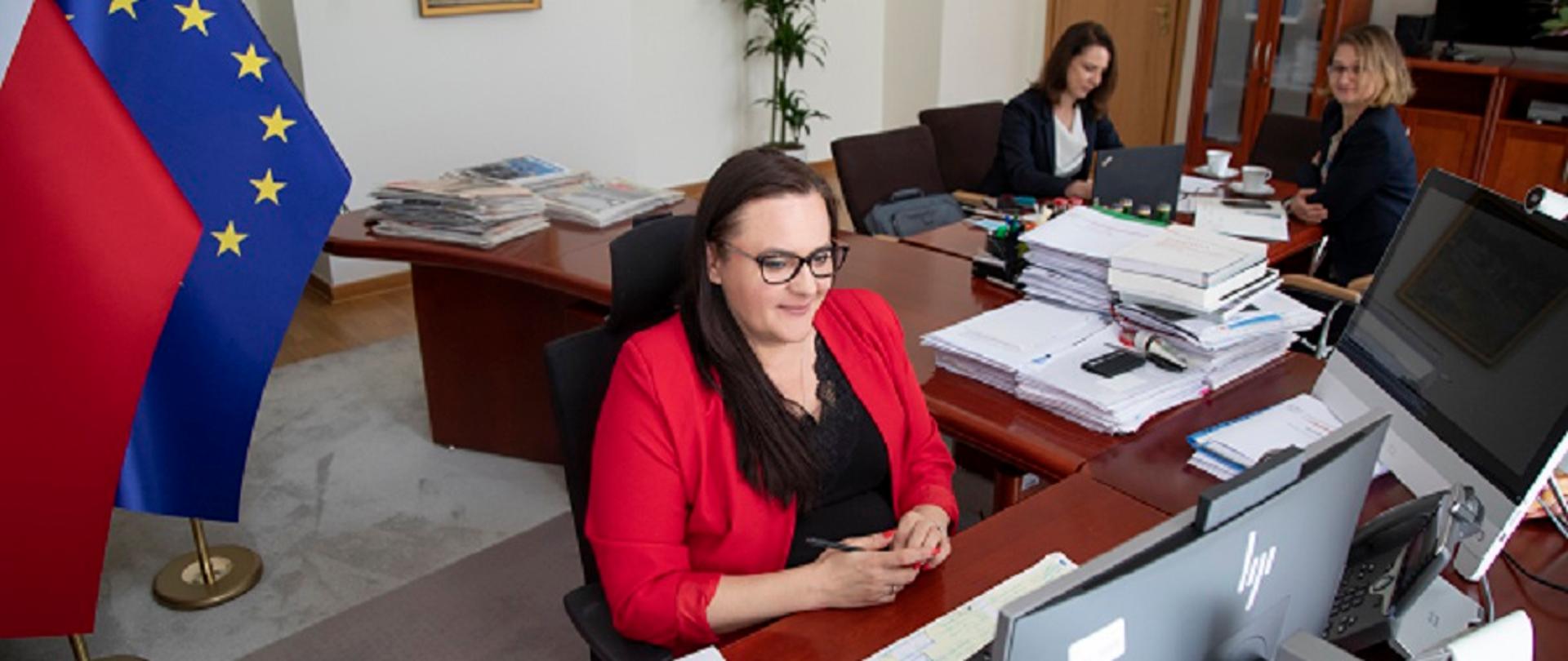 Na zdjęciu widać panią minister siedzącą za biurkiem