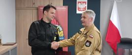 Komendant Powiatowy Państwowej Straży Pożarnej w Człuchowie st. bryg. Radosław Batruch stoi w gabinecie i wręcza akt mianowania na stanowisko zastępcy dowódcy Jednostki Ratowniczo - Gaśniczej w Człuchowie mł. kpt. Dawidowi Machnio. 