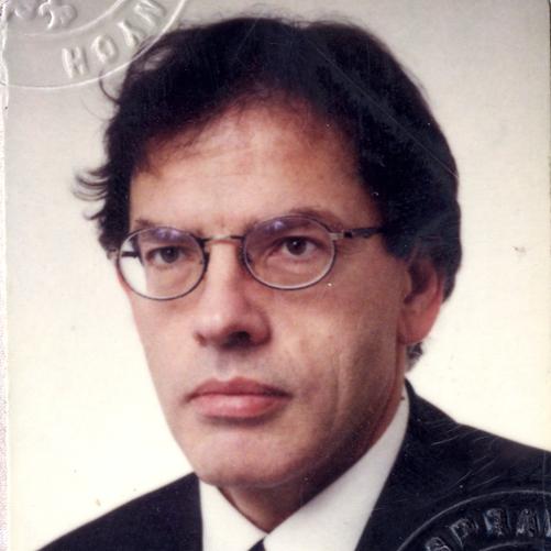 Dariusz Rosati - kolorowy portret mężczyzny, ciemne włosy, granatowa marynarka, granatowy krawat w czerwone wzory, biała koszula.