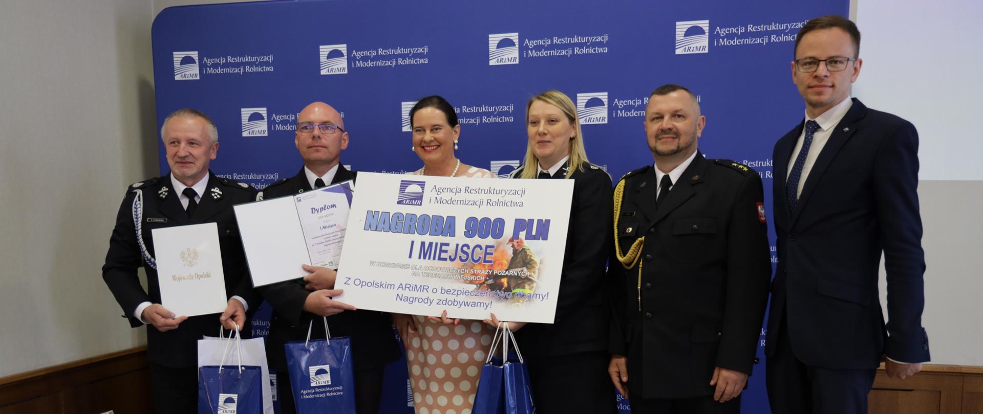 Zdjęcie przedstawia laureatów I miejsca konkursu oraz Panią Poseł Violettę Porowską oraz reprezentanta Opolskiego Komendanta Wojewódzkiego PSP kpt. Przemysława Zduna.