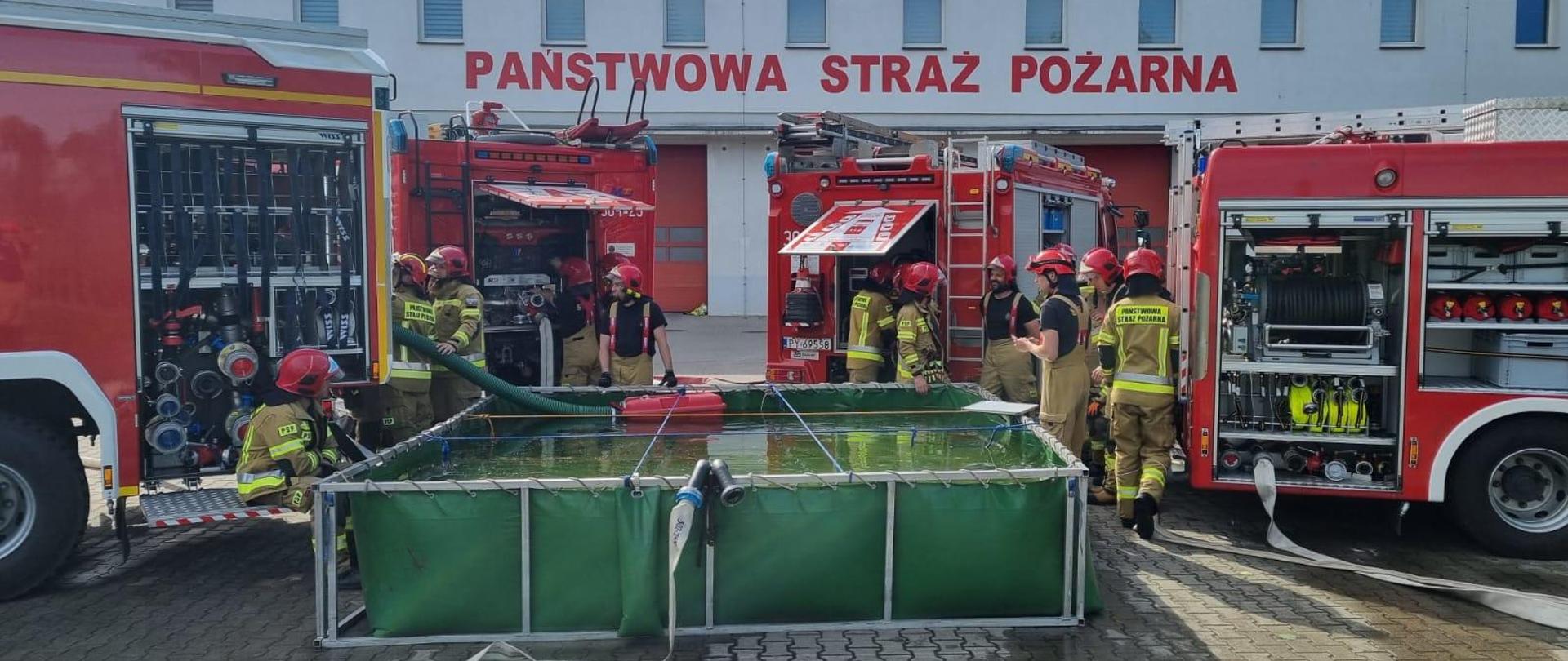 Widok z boku, zbiornik wodny, dookoła samochody i strażacy. Trwa realizacja epizodu