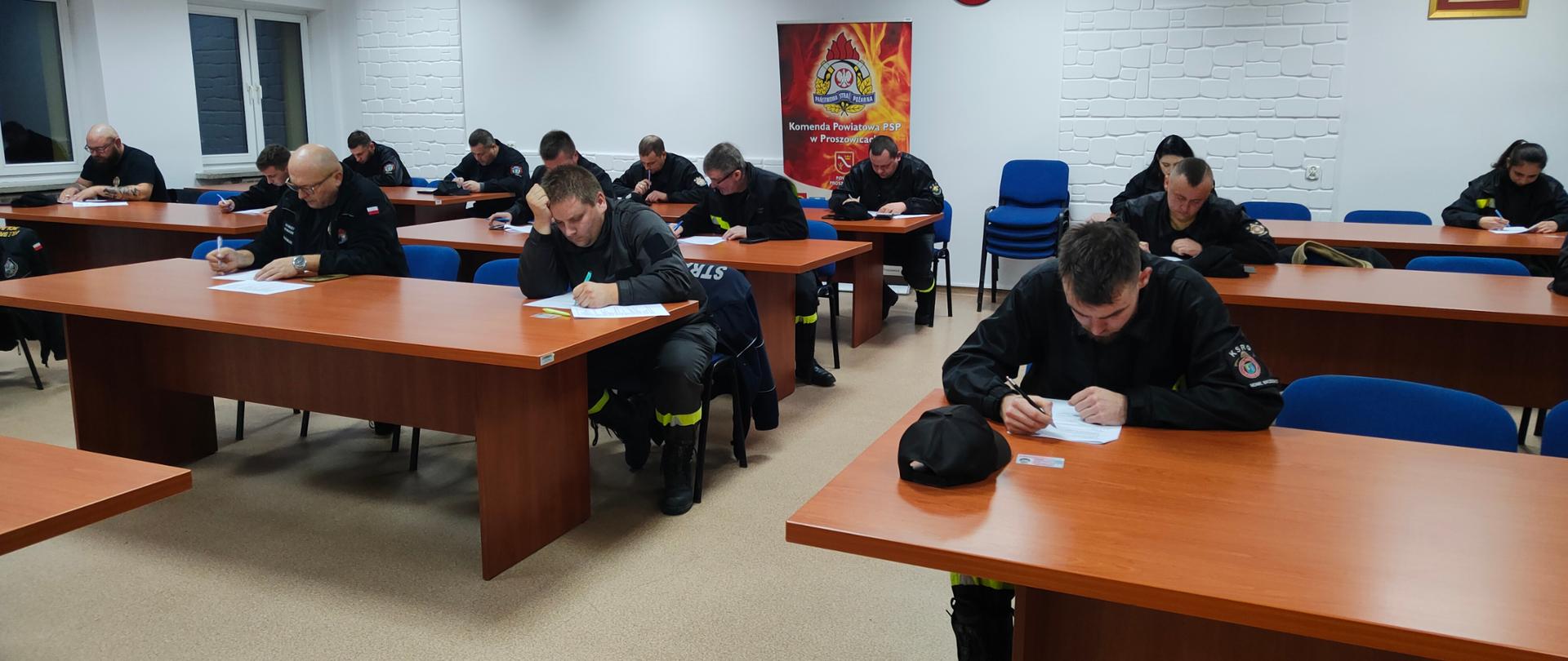 Strażacy siedzą na świetlicy i piszą egzamin