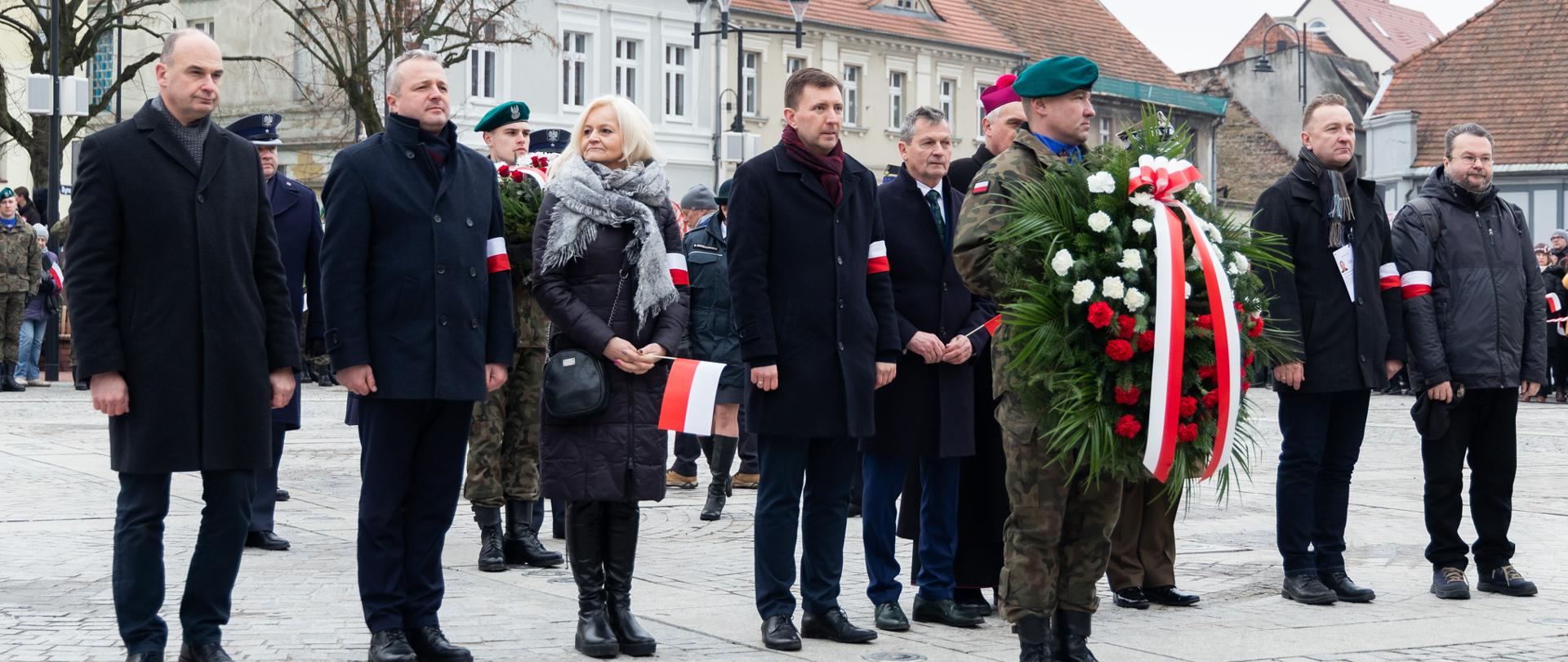 Kilka osób podczas składania kwiatów