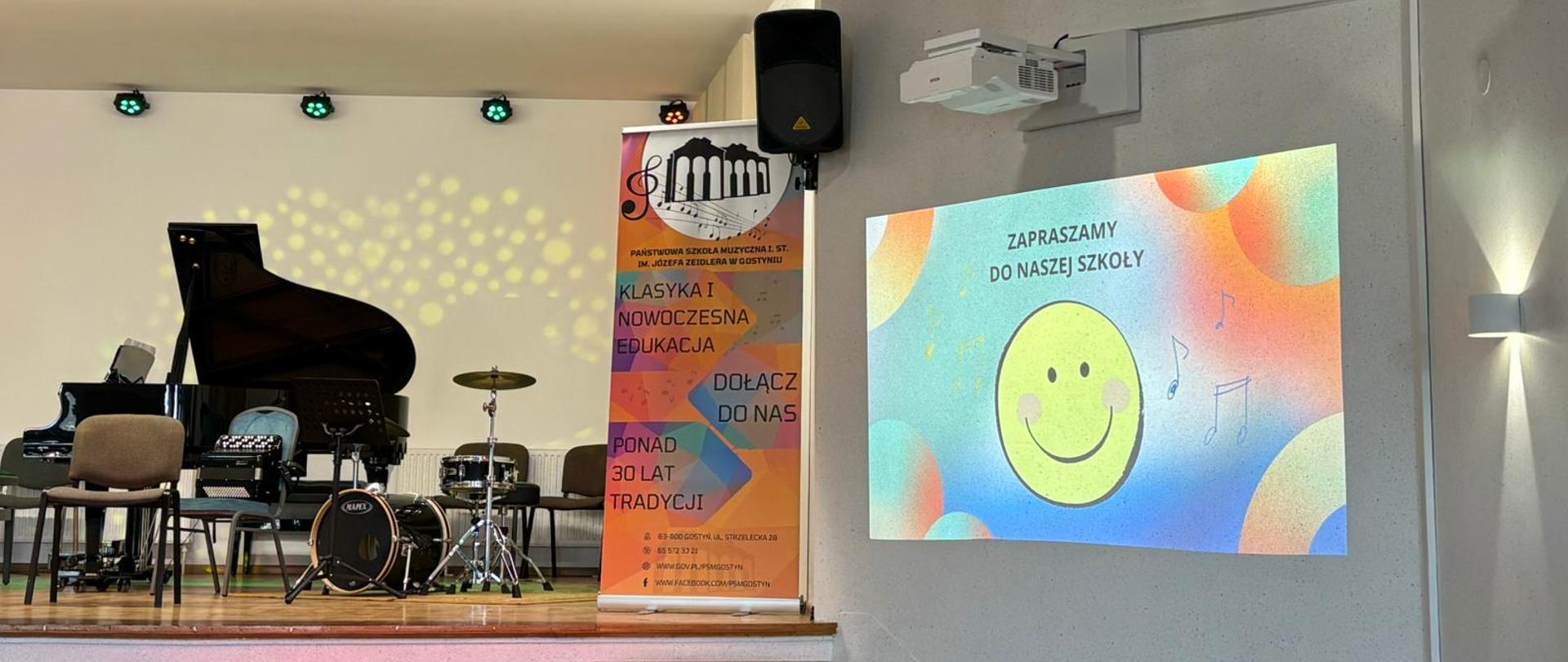 Na scenie widać fortepian ,zestaw perkusyjny i akordeon. Po prawej stonie znajduje się kolorowy rollup reklamowy. Zaraz obok wyświetlana jest prezentacja multimedialna.