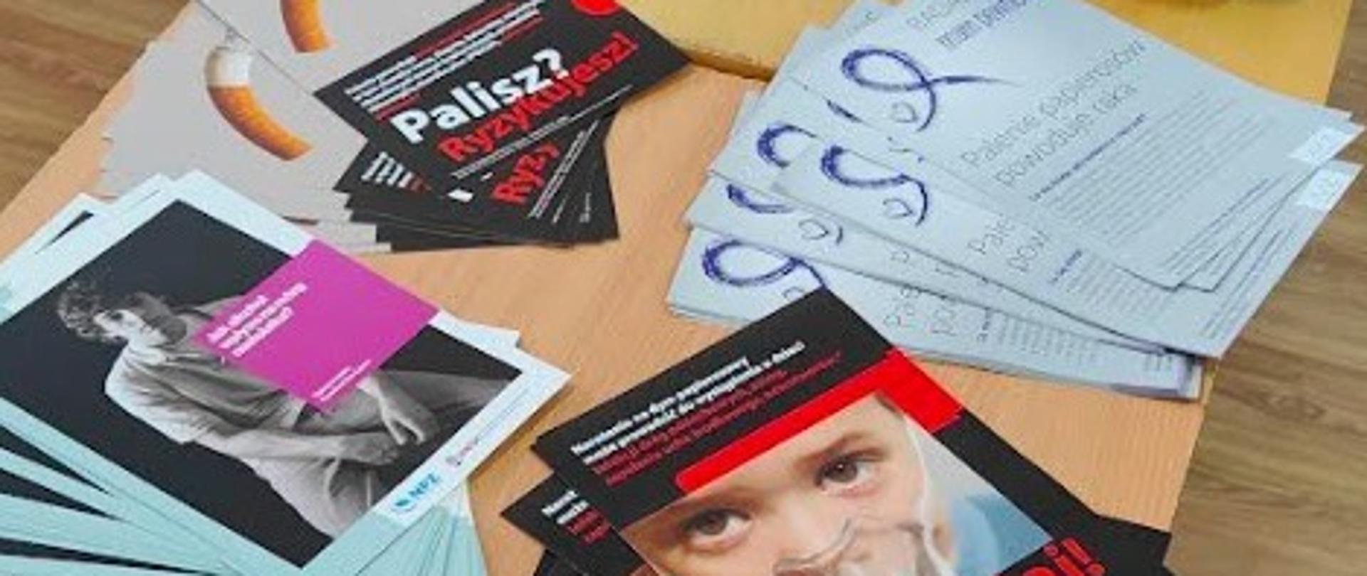 Stoisko profilaktyczno-informacyjne w ramach obchodów Światowego Dnia Rzucania Palenia. Ulotki ułożone na stole.
