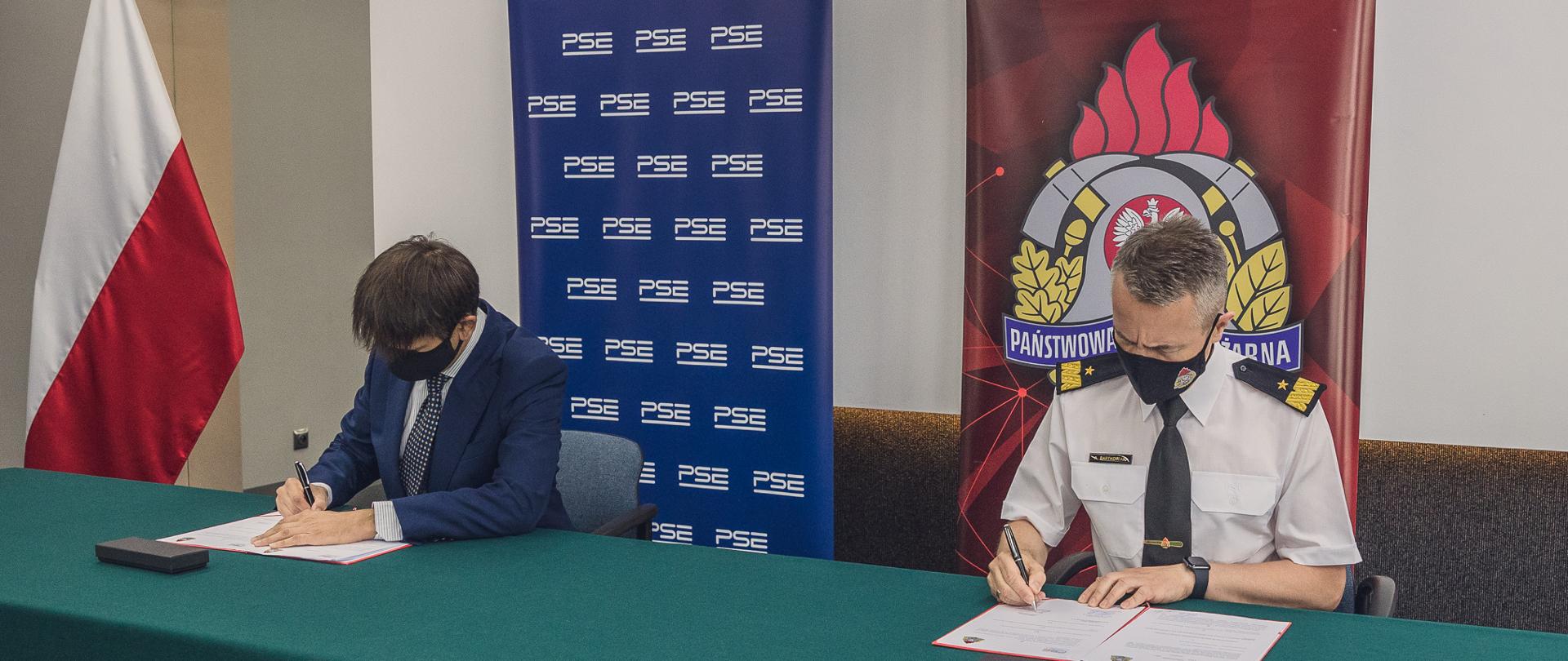 Komendant Główny PSP i Prezes PSE SA siedząc podpisują porozumienie