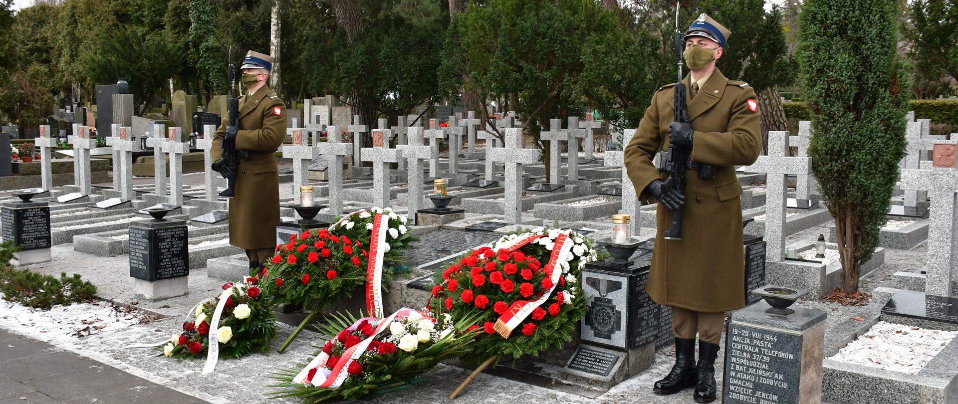 Zdjęcie przedstawia fragment wyremontowanej kwatery wojennej Zgrupowania AK „Gurt”, znajdującej się na warszawskim Cmentarzu Wojskowym na Powązkach. Przy mogile wartę pełnią żołnierze Wojska Polskiego, a tuż przed pomnikiem lezą biało-czerwone wieńce.