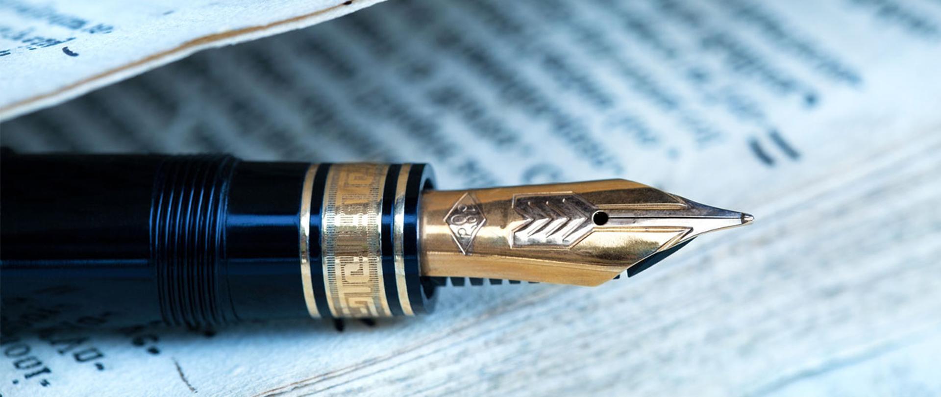 Na zdjęciu: eleganckie pióro leżące na dokumentach 