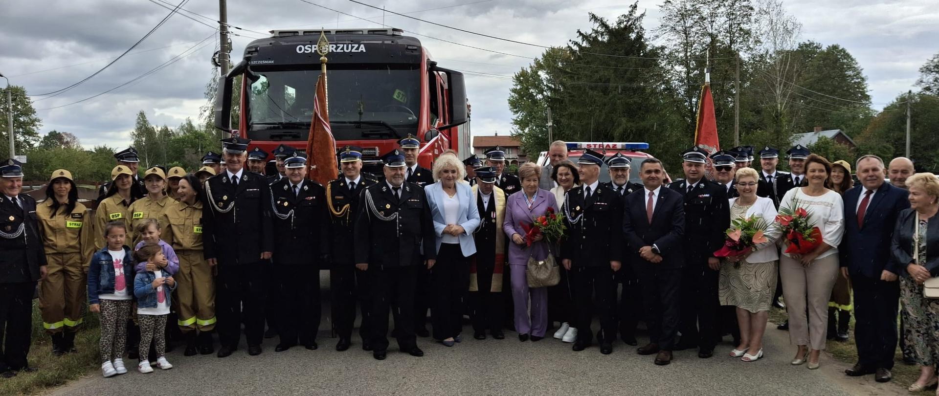 Zaproszeni goście na tle samochodów ratowniczo - gaśniczych. 