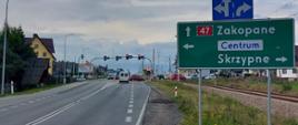 Zajęcie drogi krajowej nr 47 na odcinku Nowy Targ - Szaflary. Jedna jezdnia po jednym pasie ruchu, widoczne skrzyżowanie ze światłami i dodatkowy pas do skrętu w prawo. Po obu stronach jezdni widoczna zabudowa. Po prawej stronie znak na Zakopane. 