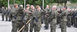 Zdjęcie przedstawia żołnierzy w mundurach moro podczas składania przysięgi na sztandar jednostki.