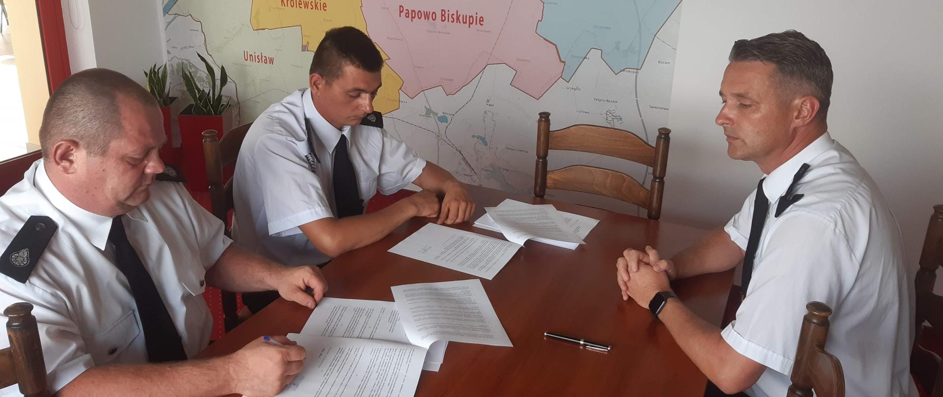Na zdjęciu znajdują się druhowie z Grzybna i Kokocka podczas podpisywania umów na szkolenie przygotowujące do egzaminu na prawo jazdy kategorii C. Zdjęcie wykonano w biurze Komendanta Powiatowego PSP w Chełmnie. 