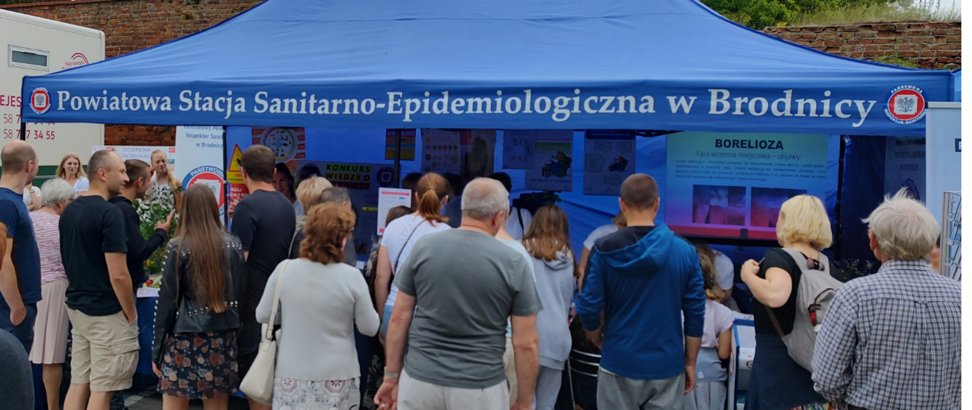 Grupa ludzi przed namiotem Powiatowej Stacji Sanitarno-Epidemiologicznej w Brodnicy podczas XV Międzynarodowego Jarmarku z królewną Anną. 