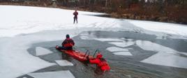 Na zdjęciu strażacy ćwiczą na zalodzonym zbiorniku wodnym