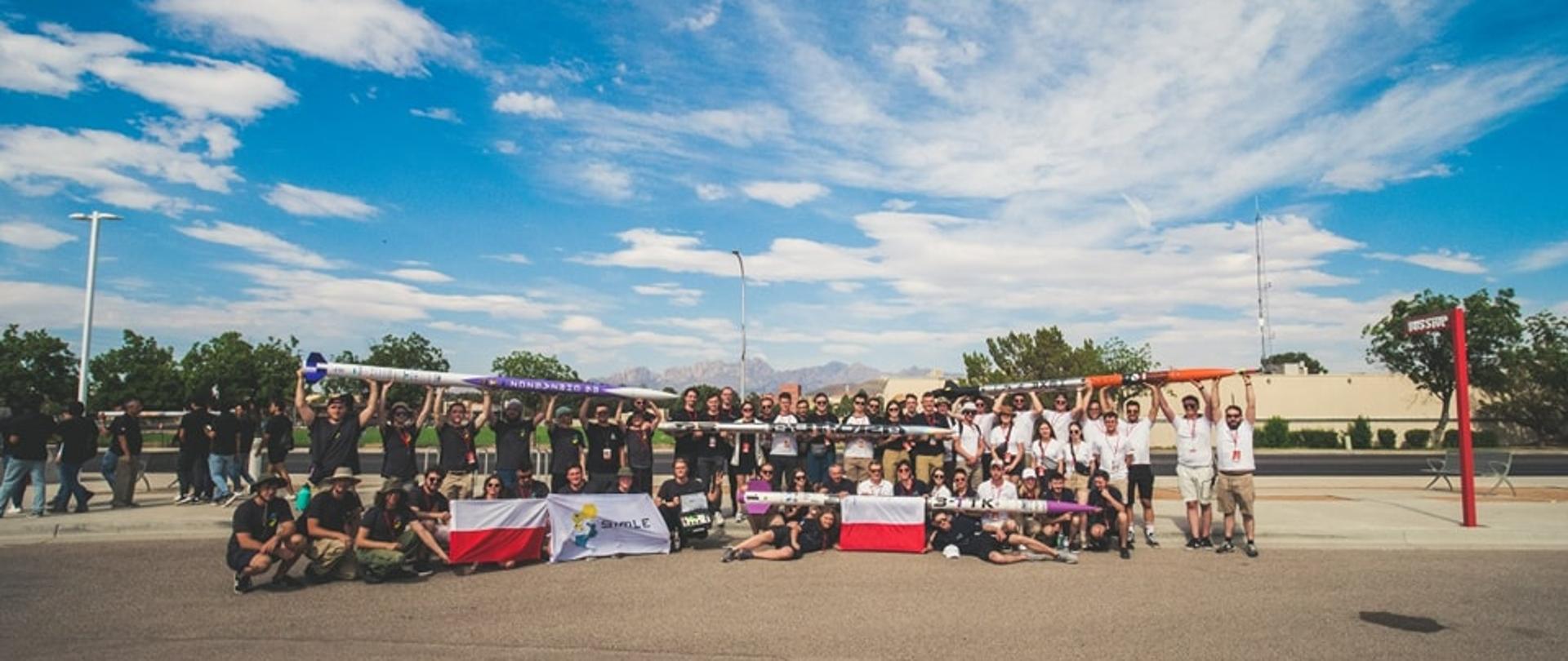 Grupa studenów przymających polskie flagi samodzielnie zbudowane rakiety. 