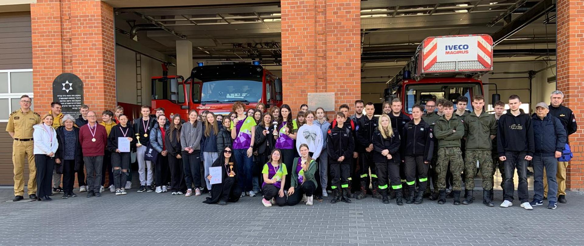Zdjęcie zbiorowe uczestników zawodów zrobione przed strażnicą.