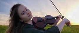 Plakat z zaproszeniem na recital dyplomowy Wiktorii Czai. NW centralnej części młoda dziewczyna ze skrzypcami w ręku siedzi na zielonej trawie i gra. Włos ma długi, rozwiany.