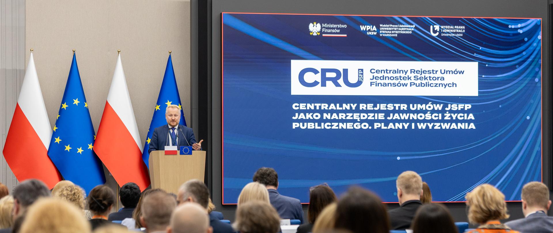 Podsekretarz stanu Jurand Drop przemawiający na konferencji dotyczącej Centralnego Rejestru Umów Jednostek Sektora Finansów Publicznych (CRU JSFP)