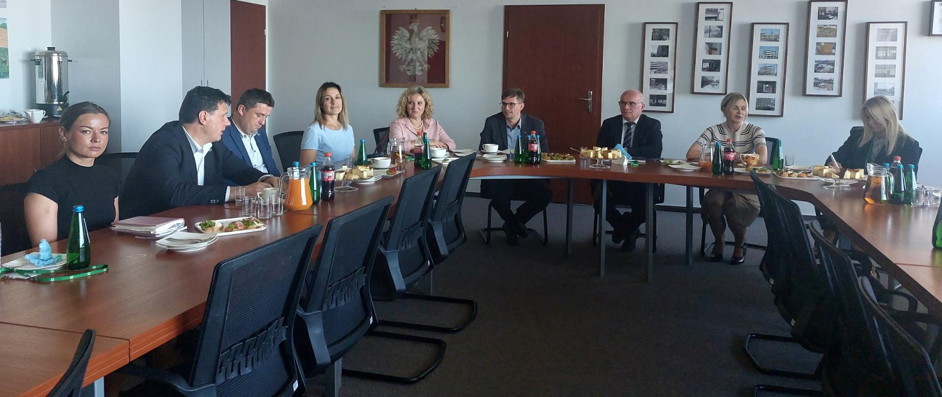 Sala obrad, grupa osób: kobiet i mężczyzn przy stole