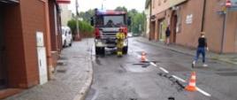 Na zdjęciu strażacy zabezpieczają uszkodzoną jezdnię