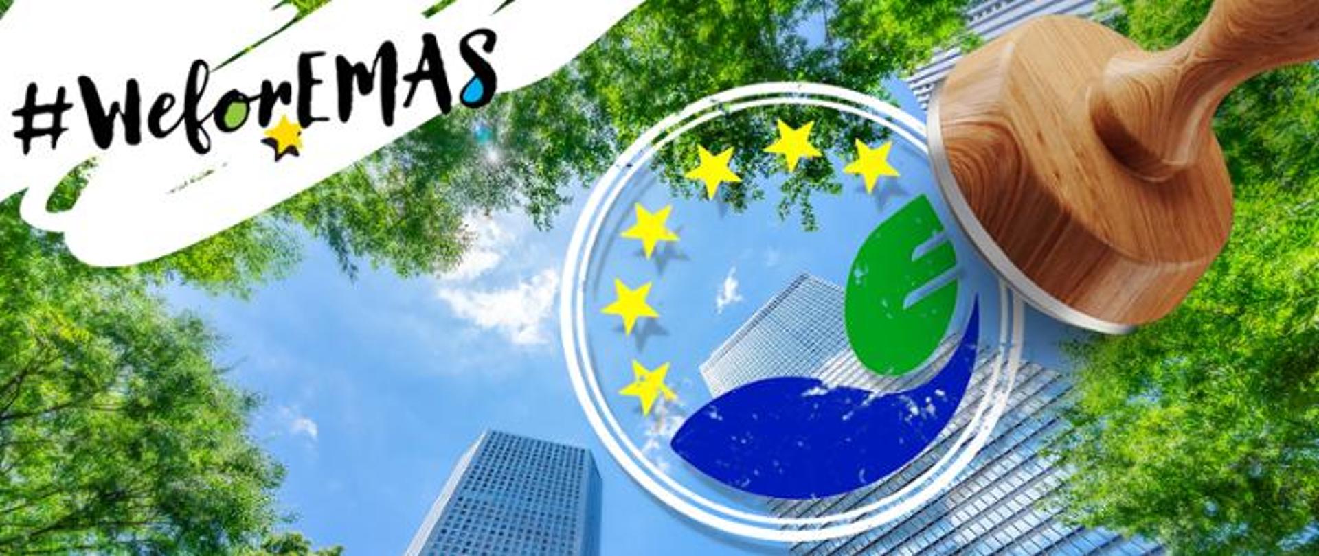 Dwa wieżowce sfotografowane od dołu na tle niebieskiego nieba. Pomiędzy nimi widać zielone drzewa. Na pierwszym planie drewniana pieczęć, która odbija logo EMAS. W lewym górnym rogu napis: #WeforEMAS.
