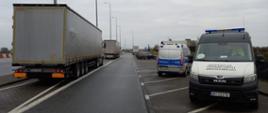 Od lewej: ciężarówka zatrzymana do kontroli drogowej i stojący obok oznakowany furgon wielkopolskiej Inspekcji Transportu Drogowego oraz oznakowany radiowóz Policji.