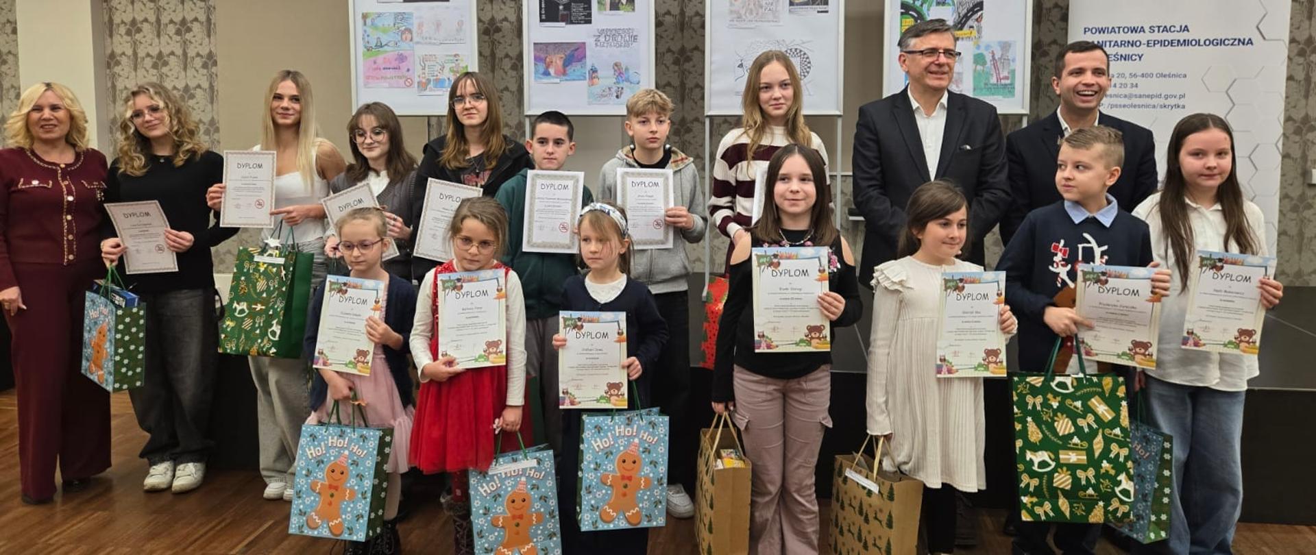 Grupa dzieci i młodzieży trzymająca dyplomy i nagrody konkursowe