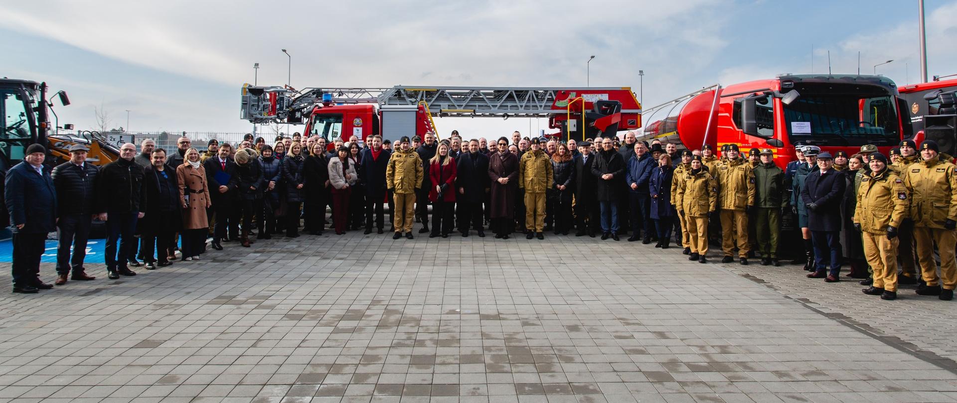Grupę zdjęcie ludzi. w tle samochody pożarnicze.