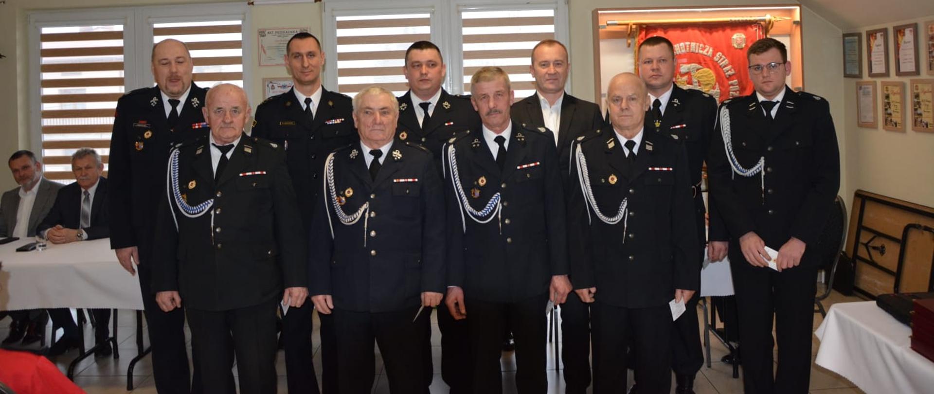 Zdjęcie przedstawia gości i organizatorów na zebraniu sprawozdawczym w jednostce OSP.