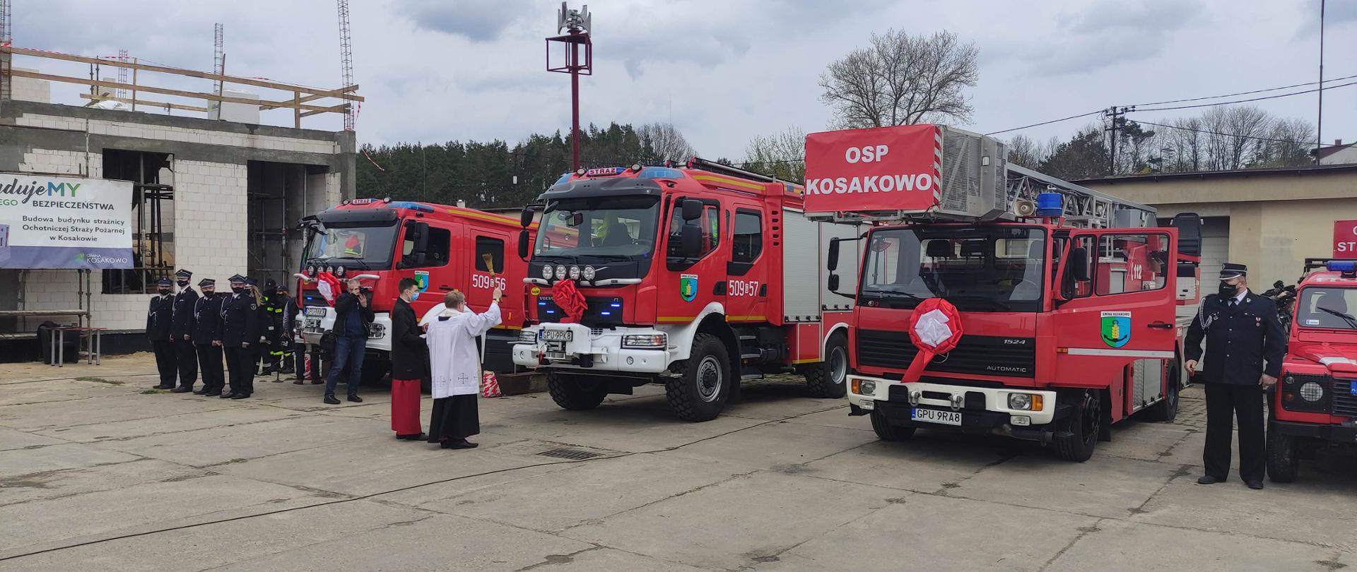 Ksiądz kanonik święci samochody pożarnicze w obecności druhów OSP Kosakowo.