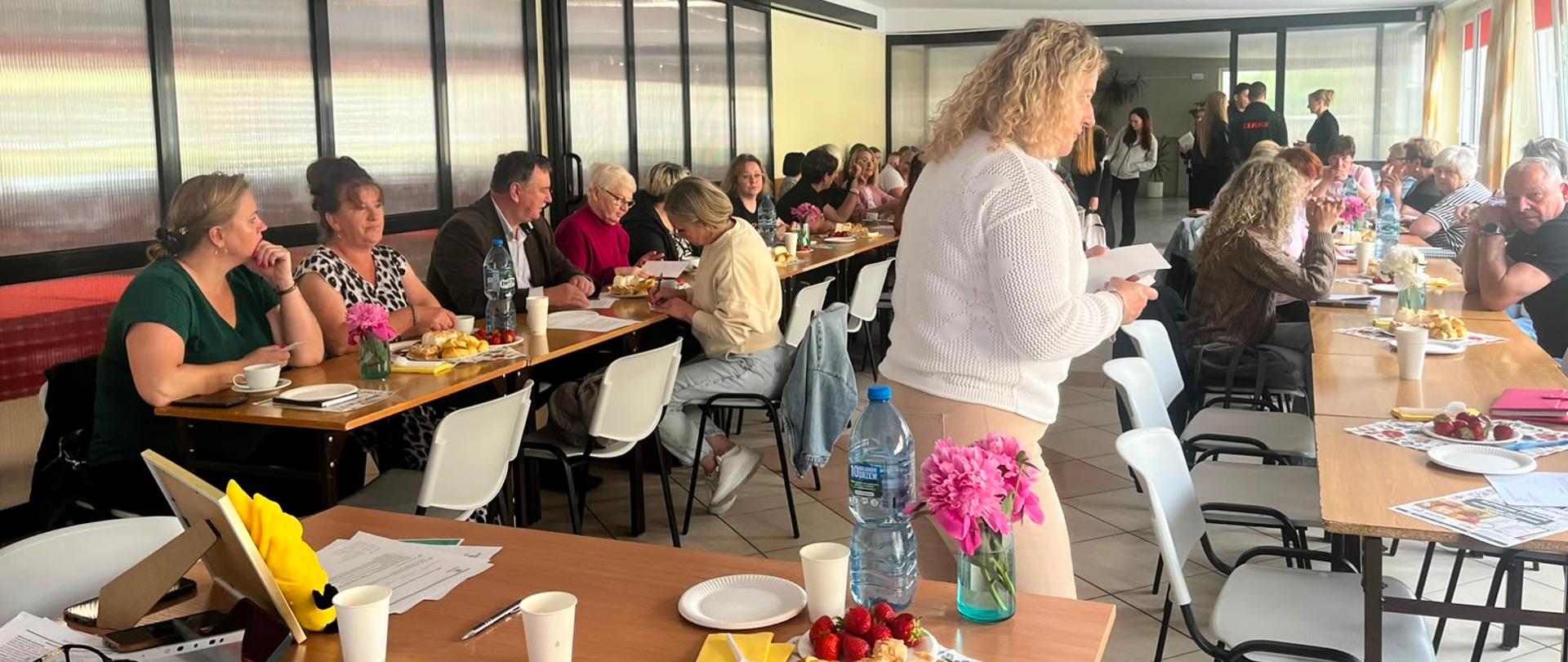 Sala pełna uczestników warsztatów. Wszyscy z uwagą słuchają Inspektorki prowadzącej spotkanie. Uczestnicy siedzą na krzesłach, aktywnie angażują się w zajęcia i biorą udział w dyskusji