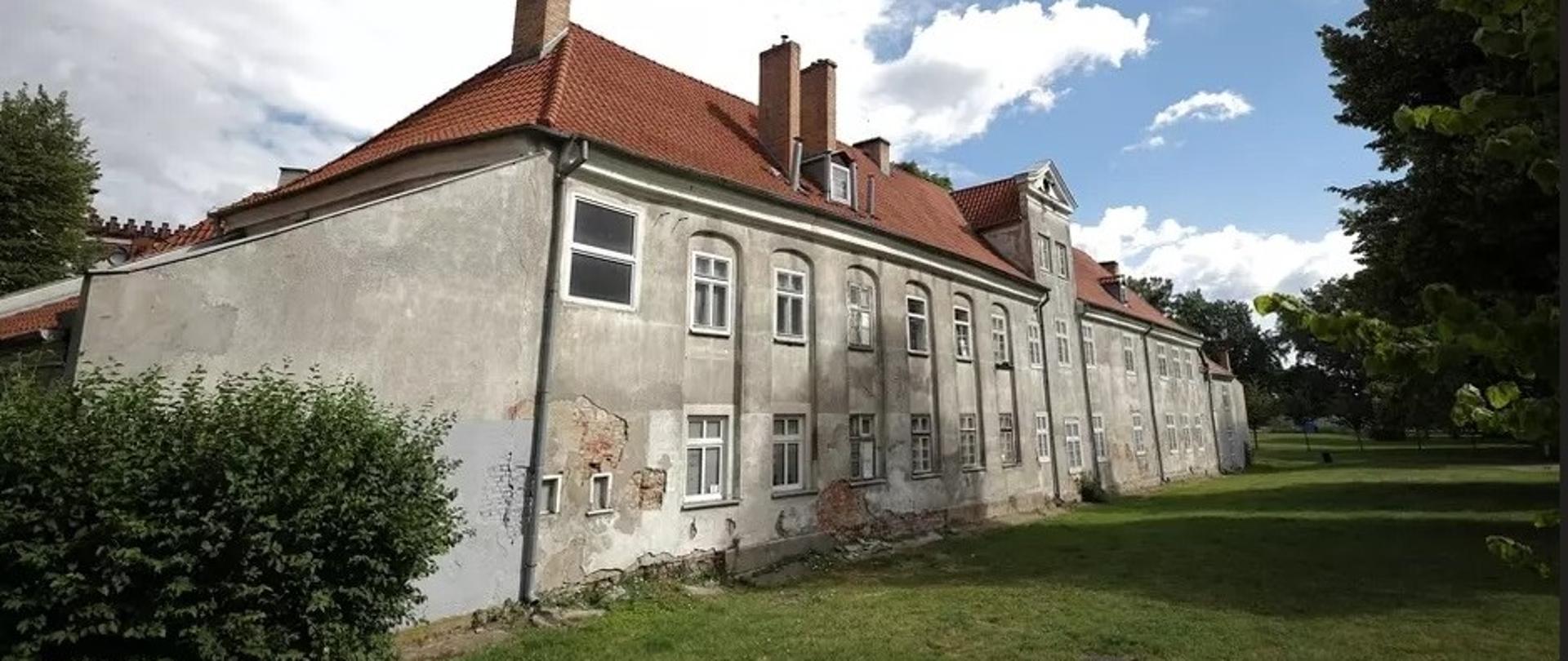 Budynek siedemnastowiecznego budynku sierocińca, odpadający tynk, wokół krzewy