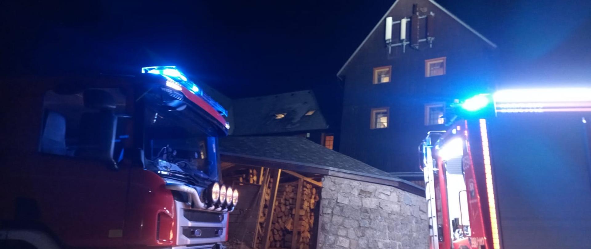 Na zdjęciu widać dwie jednostki straży pożarnej. W tle widać zabudowania obiektu Hala Szrenicka. W tym obiekcie zapaliła się sadza w przewodzie kominowym. Zdjęcie wykonane jest w nocy. 