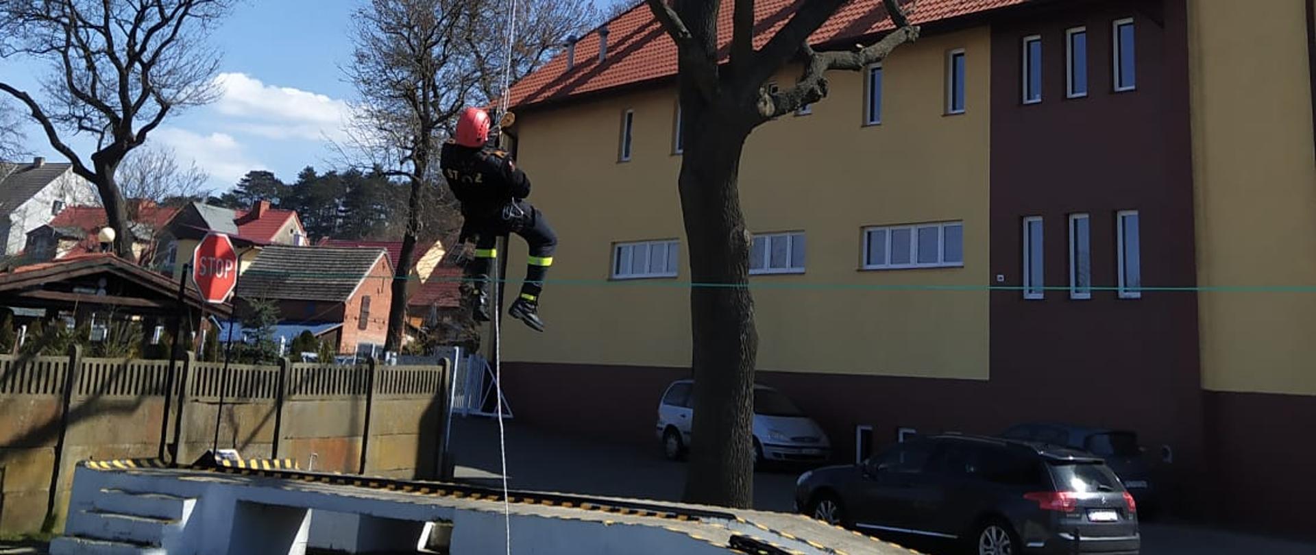 Ćwiczenia wysokościowe na tle budynku komendy.